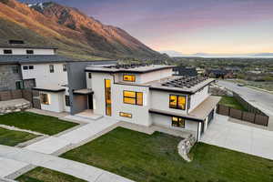 Modern home with fence, a garage, stucco siding, a mountain view, and driveway
