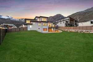 Back of property with stucco siding, a fenced backyard, a mountain view, and a yard