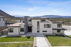 View of front of house featuring a front lawn, a mountain view, and stucco siding