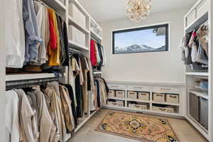 Spacious closet with light tile patterned floors and a notable chandelier