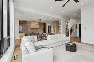 Living room featuring recessed lighting, ceiling fan, light wood-style flooring, and stairway