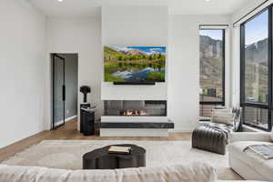 Living room with a glass covered fireplace, baseboards, and wood finished floors
