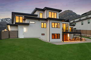 Back of property with a mountain view, stucco siding, and a yard