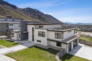 Modern home featuring stucco siding, a mountain view, driveway, and fence