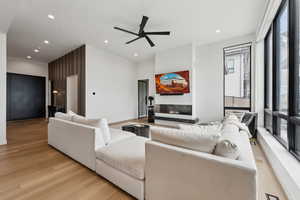 Living room featuring a glass covered fireplace, recessed lighting, a ceiling fan, and light wood finished floors