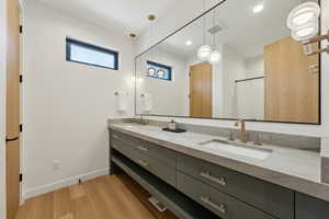 Bathroom with double vanity, baseboards, a sink, and wood finished floors