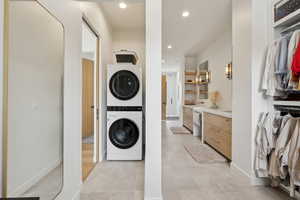 Laundry room with stacked washing maching and dryer, light tile patterned floors, laundry area, and recessed lighting