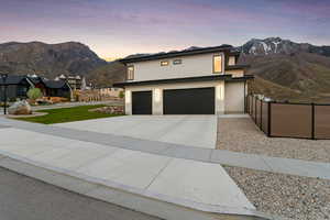Contemporary house featuring a garage, a mountain view, driveway, and fence