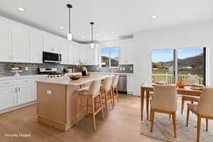 Kitchen with stainless steel appliances, backsplash, light wood-style flooring, a center island, and recessed lighting