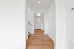 Corridor featuring recessed lighting, baseboards, hardwood flooring, and stairway