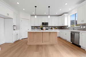 Kitchen with mitered edge quartz countertops, white cabinets, hardwood flooring, appliances with stainless steel finishes, and gray backsplash