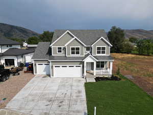 View of front of property featuring a porch, a mountain view, roof with shingles, and concrete driveway