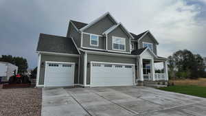 View of front facade with concrete driveway, an attached garage, and a shingled roof