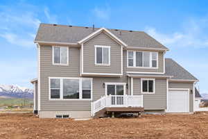 Rear view of property featuring an attached garage, a mountain view, and roof with shingles