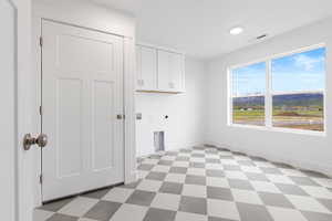 Laundry area with hookup for an electric dryer, cabinet space, and tile floor