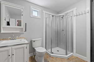 Bathroom with baseboards, vanity, toilet, and a shower stall