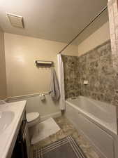 Bathroom with vanity, toilet, a textured ceiling, and shower / tub combo with curtain