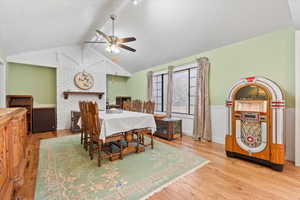 Dining area featuring vaulted ceiling with beams, ceiling fan, wainscoting, and wood finished floors