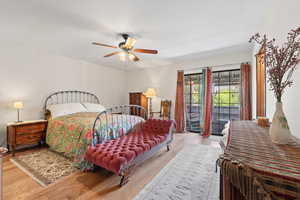 Bedroom featuring a ceiling fan, wood finished floors, and access to exterior