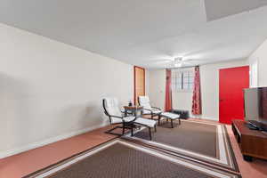 Living area featuring carpet flooring, ceiling fan, and baseboards