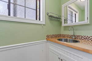 Interior space with a textured wall, a sink, and a wainscoted wall