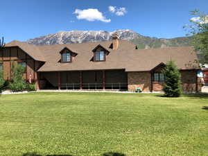 View of front of home with brick siding, a chimney, a mountain view, and a front yard