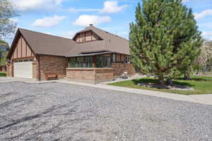 View of front facade with roof with shingles, brick siding, a garage, a sunroom, and concrete driveway