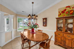 Dining room featuring crown molding, a chandelier, visible vents, and light tile patterned floors