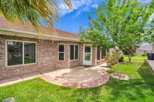 Rear view of house with a yard, a patio area, and brick siding