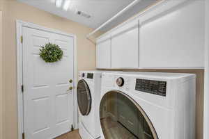 Laundry room with visible vents, cabinet space, light tile patterned flooring, and washer and dryer