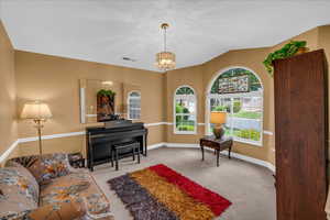 Living area featuring baseboards, visible vents, carpet flooring, and a notable chandelier
