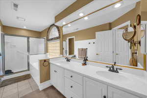 Full bathroom with double vanity, visible vents, a sink, and a stall shower