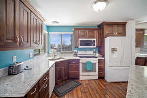 Kitchen featuring a healthy amount of sunlight, white appliances, light countertops, and a sink