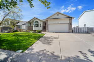 Ranch-style house featuring driveway, a gate, brick siding, a front lawn, and a garage