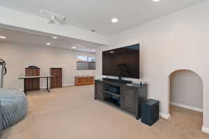Living room with arched walkways, visible vents, light colored carpet, and recessed lighting