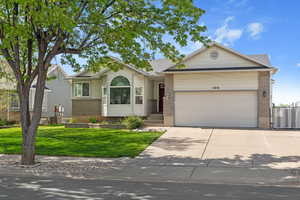 Ranch-style home with brick siding, driveway, central AC, a front yard, and an attached garage