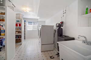 Washroom with light floors, a sink, laundry area, and washer and clothes dryer