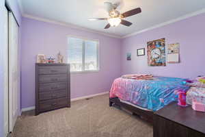 Bedroom featuring a closet, crown molding, a ceiling fan, light carpet, and baseboards