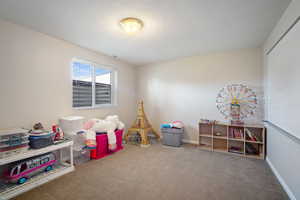 Recreation room featuring carpet, visible vents, baseboards, and a textured ceiling