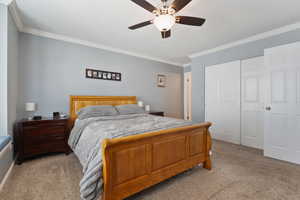 Bedroom with light colored carpet, a ceiling fan, ornamental molding, and a closet