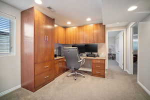 Office space with recessed lighting, visible vents, built in study area, baseboards, and light colored carpet