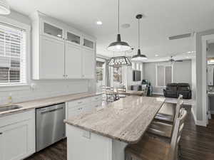 Kitchen featuring stainless steel dishwasher, recessed lighting, dark wood-style flooring, and white cabinets