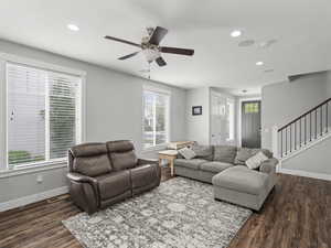 Living area featuring baseboards, ceiling fan, wood finished floors, and stairway