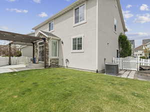Rear view of property with stucco siding, central AC, a yard, and fence