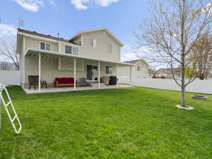 Rear view of house featuring a patio, a fenced backyard, and a lawn