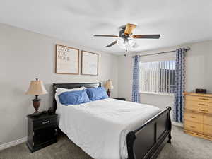 Carpeted bedroom featuring plenty of natural light and a ceiling fan