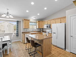 Kitchen featuring light brown cabinetry, white appliances, and a healthy amount of sunlight