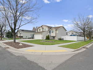Traditional-style home featuring fence, a front yard, concrete driveway, an attached garage, and a residential view