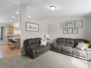 Living room with light tile patterned floors, light carpet, recessed lighting, and lofted ceiling