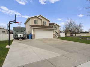 View of front of property featuring fence, an attached garage, a front lawn, brick siding, and driveway